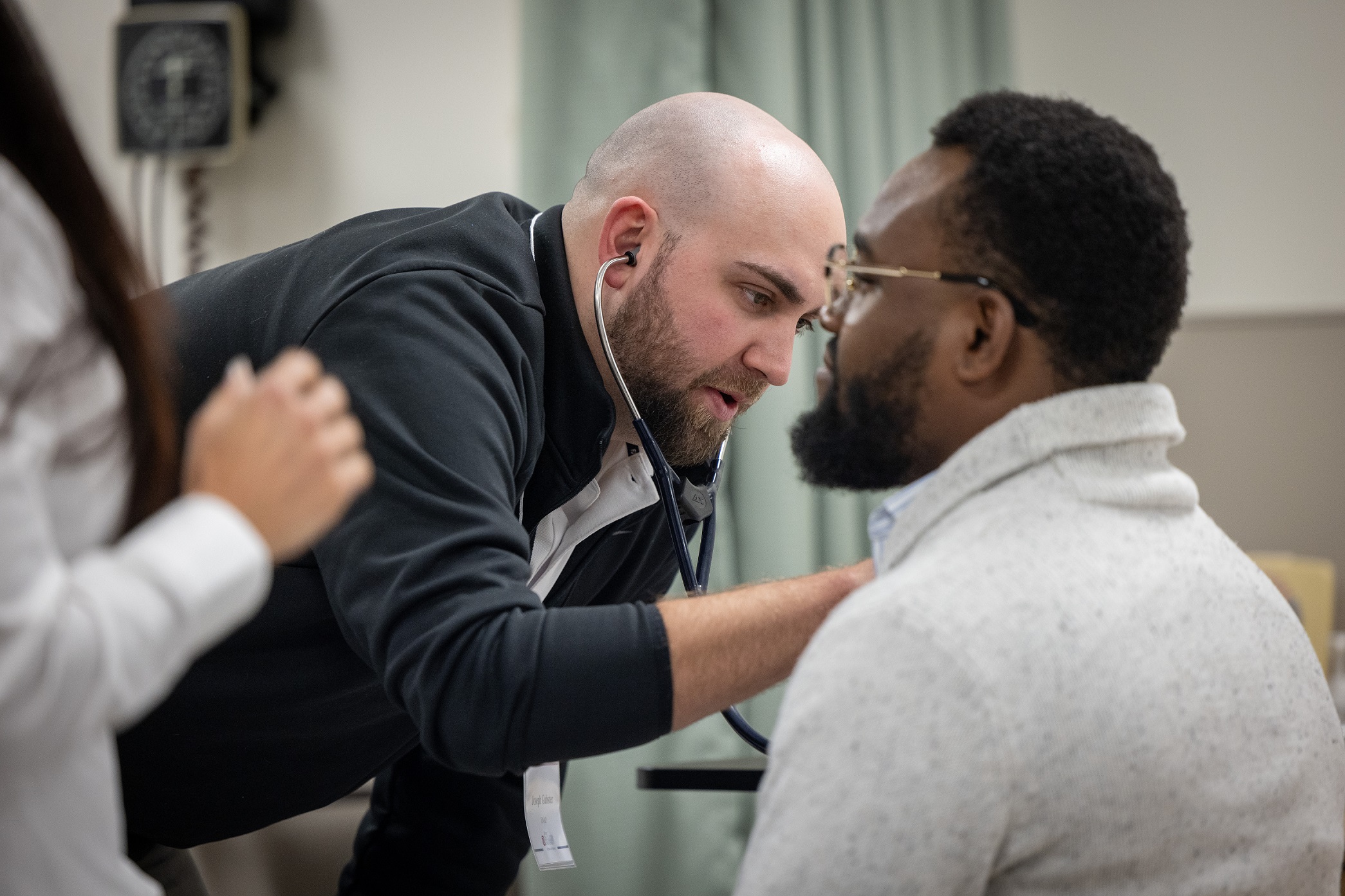 A nursing graduate student uses a stethoscope on a volunteer. 