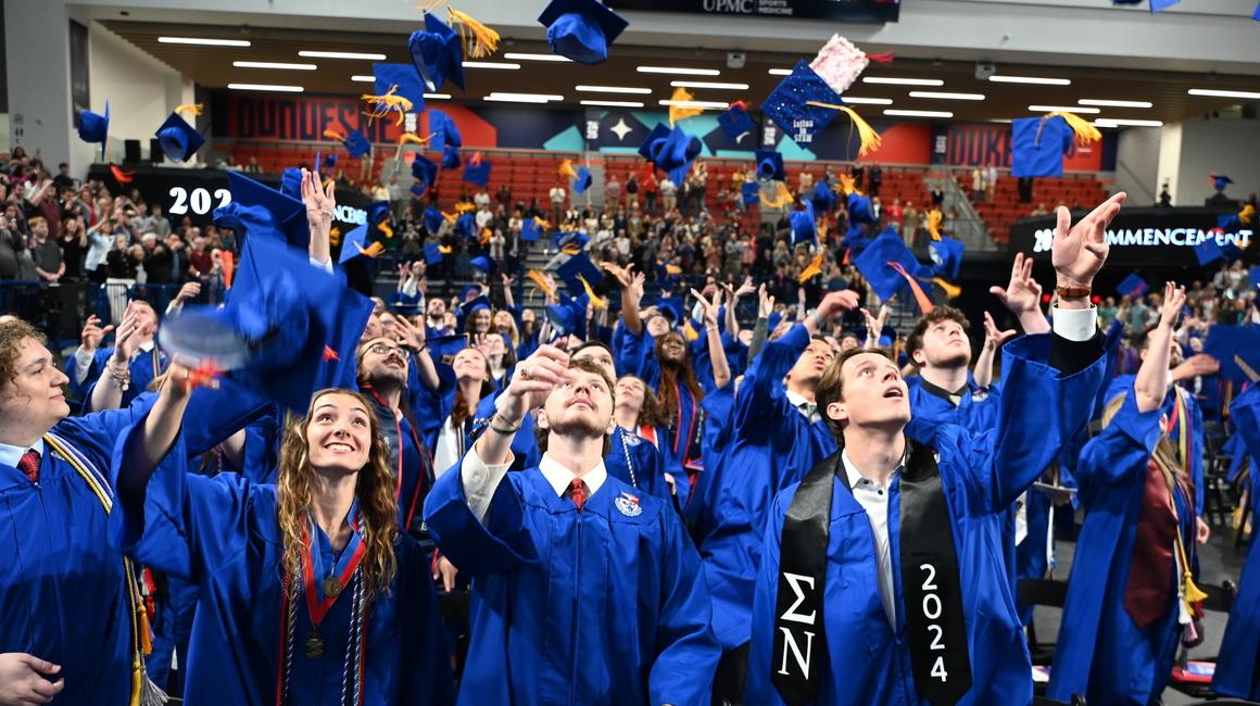 Students throwing mortarboards in the air at their Duquesne University graduation.